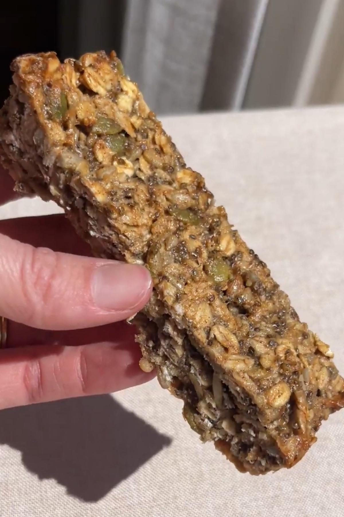 Close-up of a chewy nut-free granola bar showing oats, sunflower seeds, pumpkin seeds, and chia seeds.