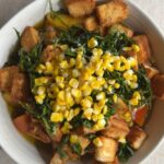 Overhead view of peach panzella salad topped with basil, corn, and croutons.