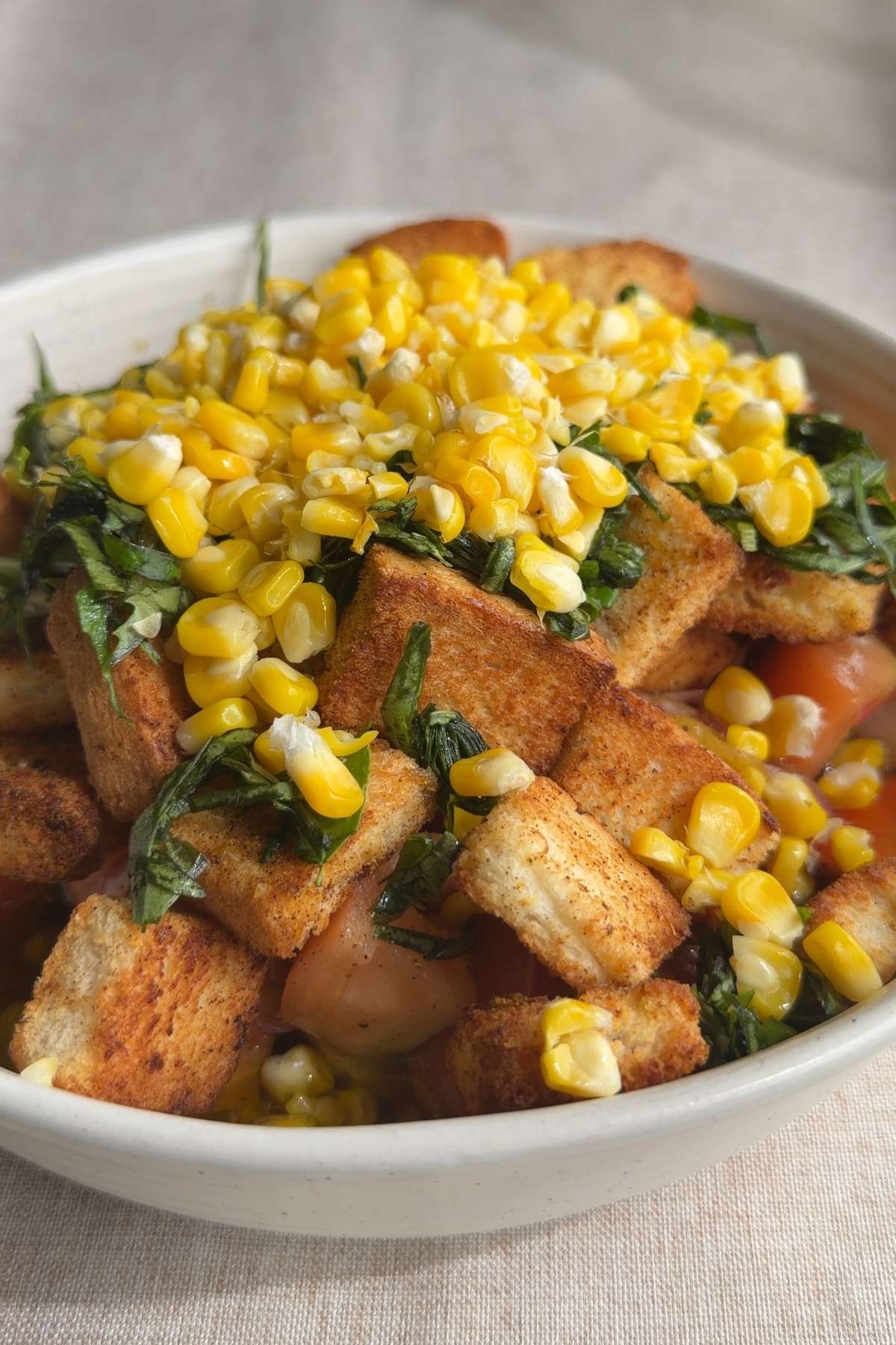 Peach and corn panzella salad topped with toasted croutons and fresh basil.