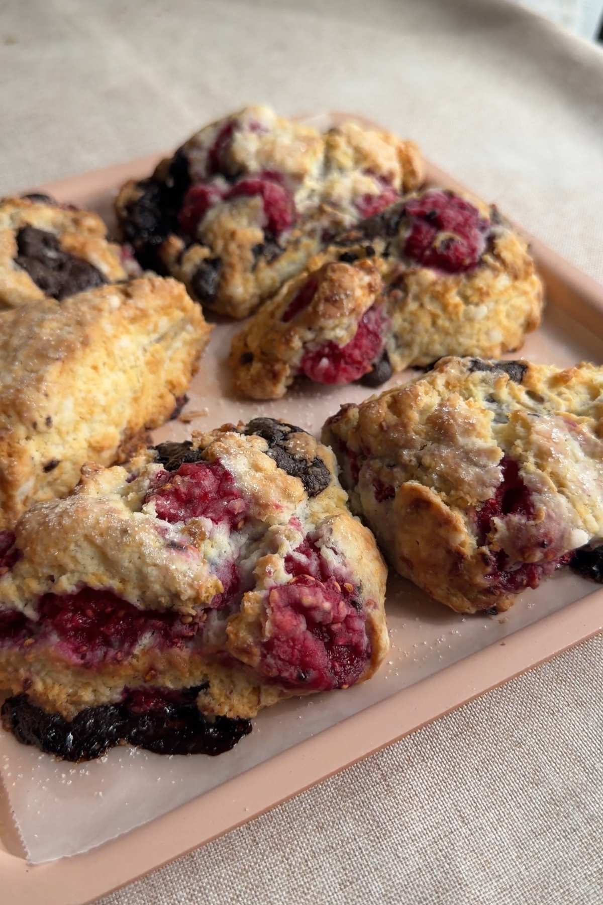 Fresh raspberry chocolate scones on a tray with juicy berries and dark chocolate.