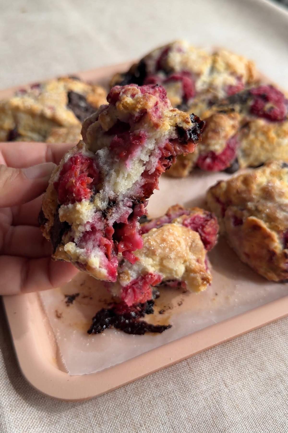 Broken raspberry chocolate scone showing a soft crumb with juicy berries and dark chocolate.
