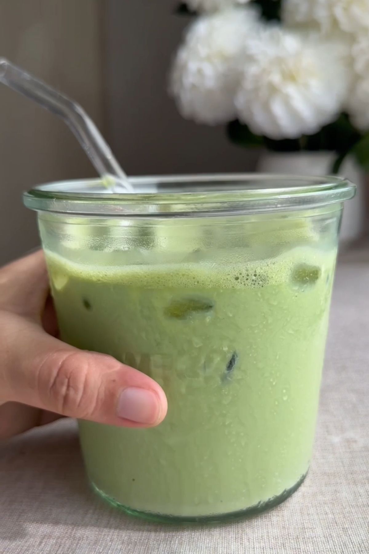 Iced green latte in a glass with a straw.