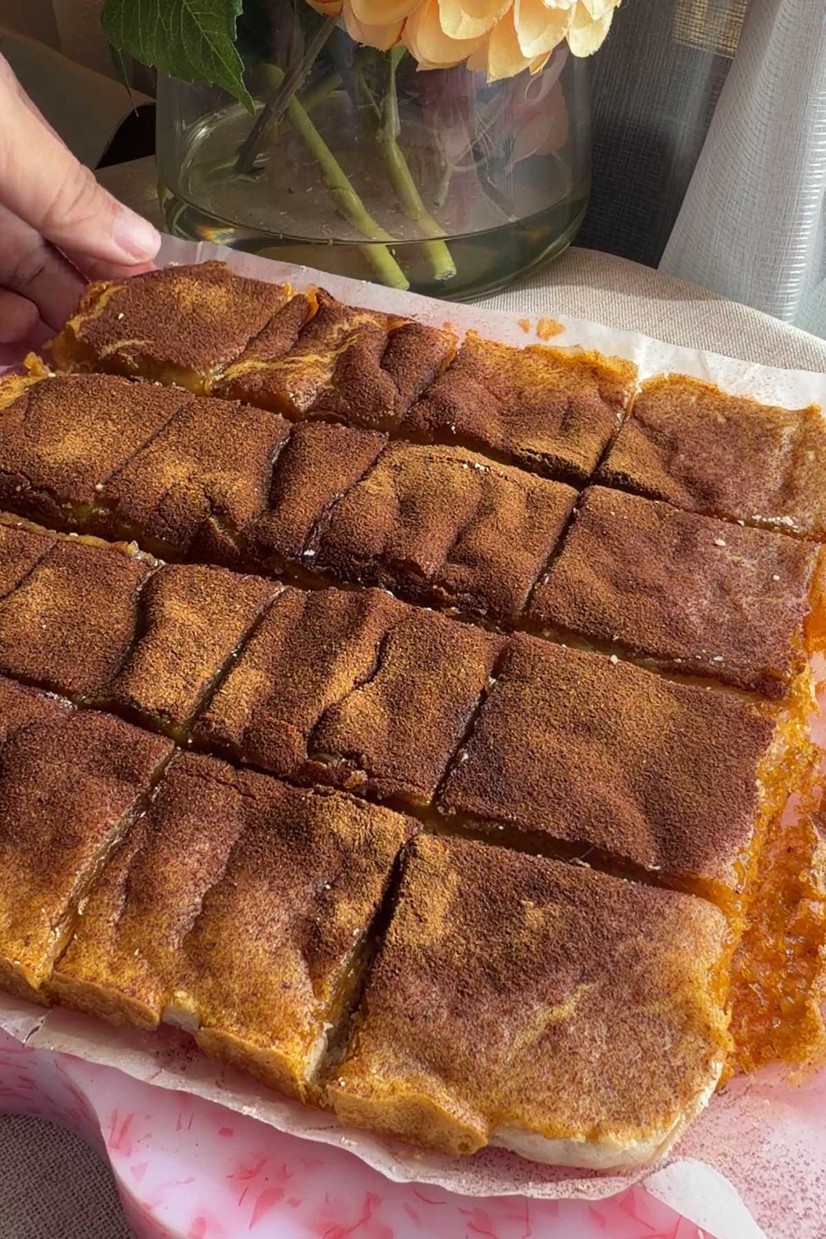 Tray of sliced vegan sweet potato pie bars dusted with cinnamon.