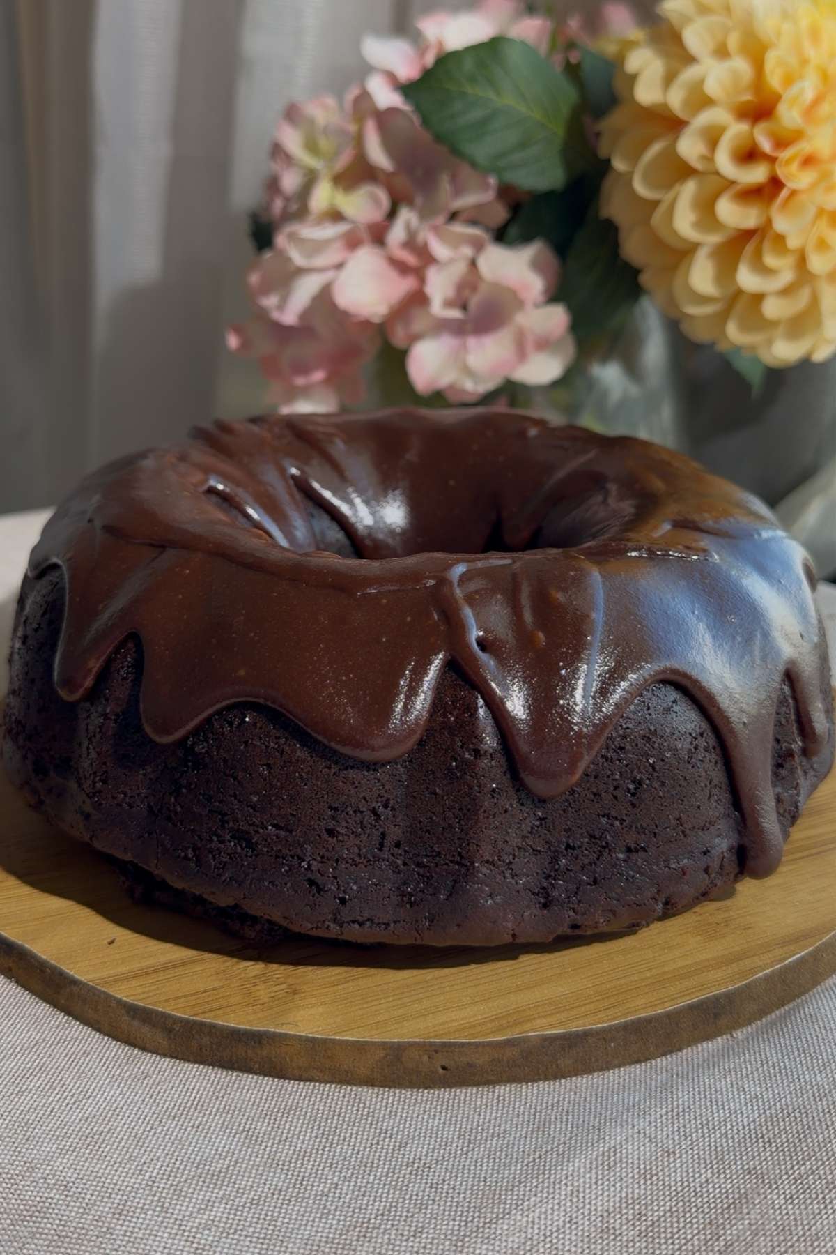 Pouring glossy chocolate icing over a chocolate Bundt cake.