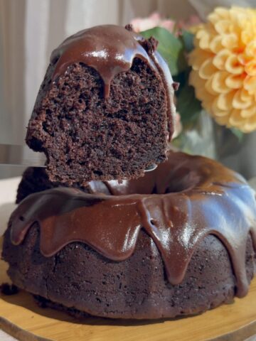 A slice lifted from a chocolate Bundt cake topped with glossy chocolate icing.