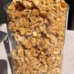 Container filled with crunchy vanilla almond granola made with oats and sliced almonds.