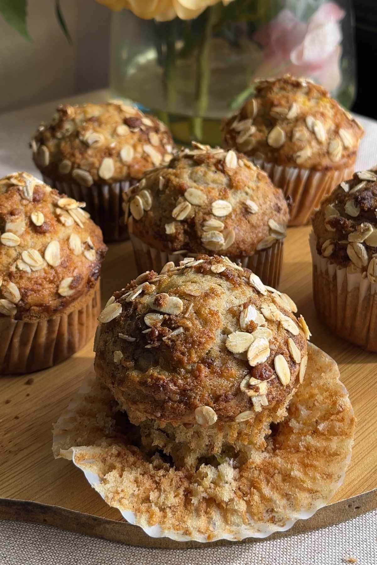 Banana muffin with the paper liner peeled back to show the soft crumb.
