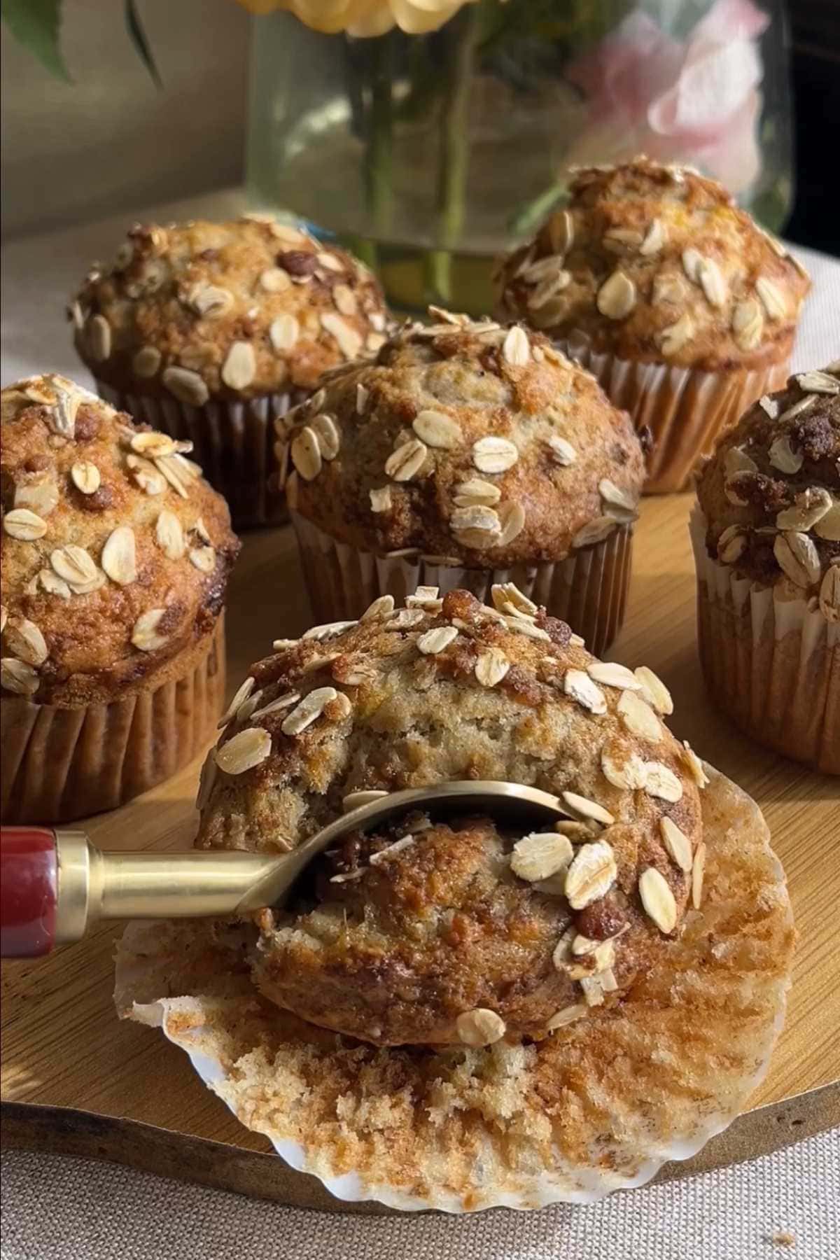 Spoon lifting a piece from a banana muffin with rolled oat topping.