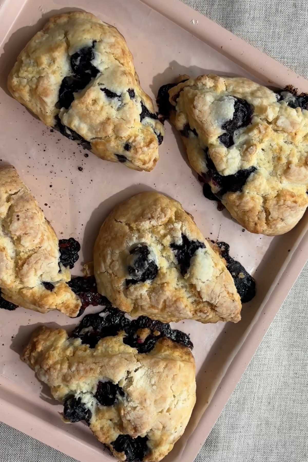 Overhead view of freshly baked blueberry scones on a baking tray.