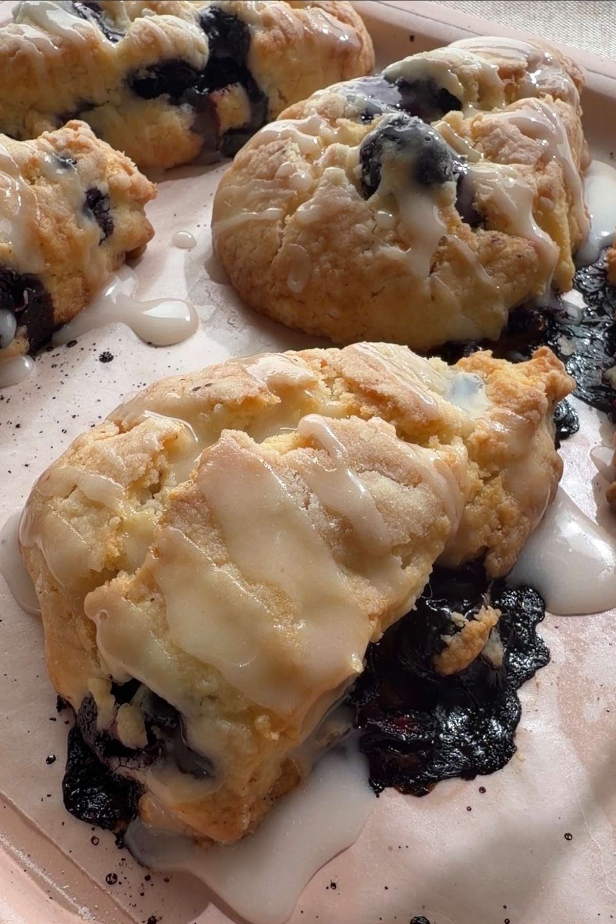 Close-up of glazed blueberry scones with baked blueberries bursting through.