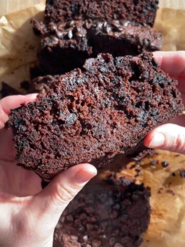Slice of vegan chocolate zucchini bread showing a moist, chocolatey crumb.