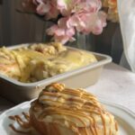 Cinnamon roll on a plate with thick frosting and caramel drizzle.