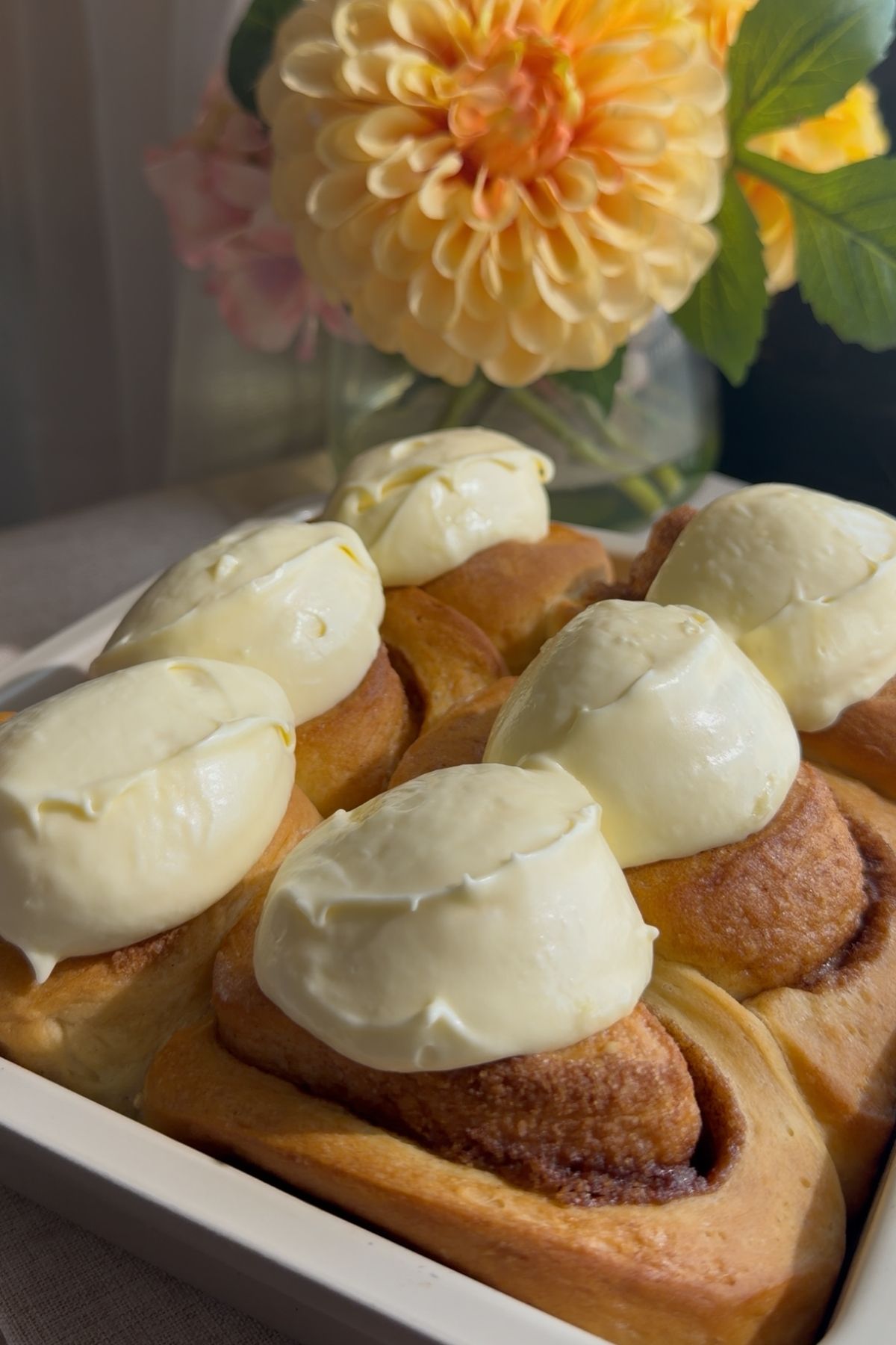 Baked cinnamon rolls topped with dollops of thick frosting.