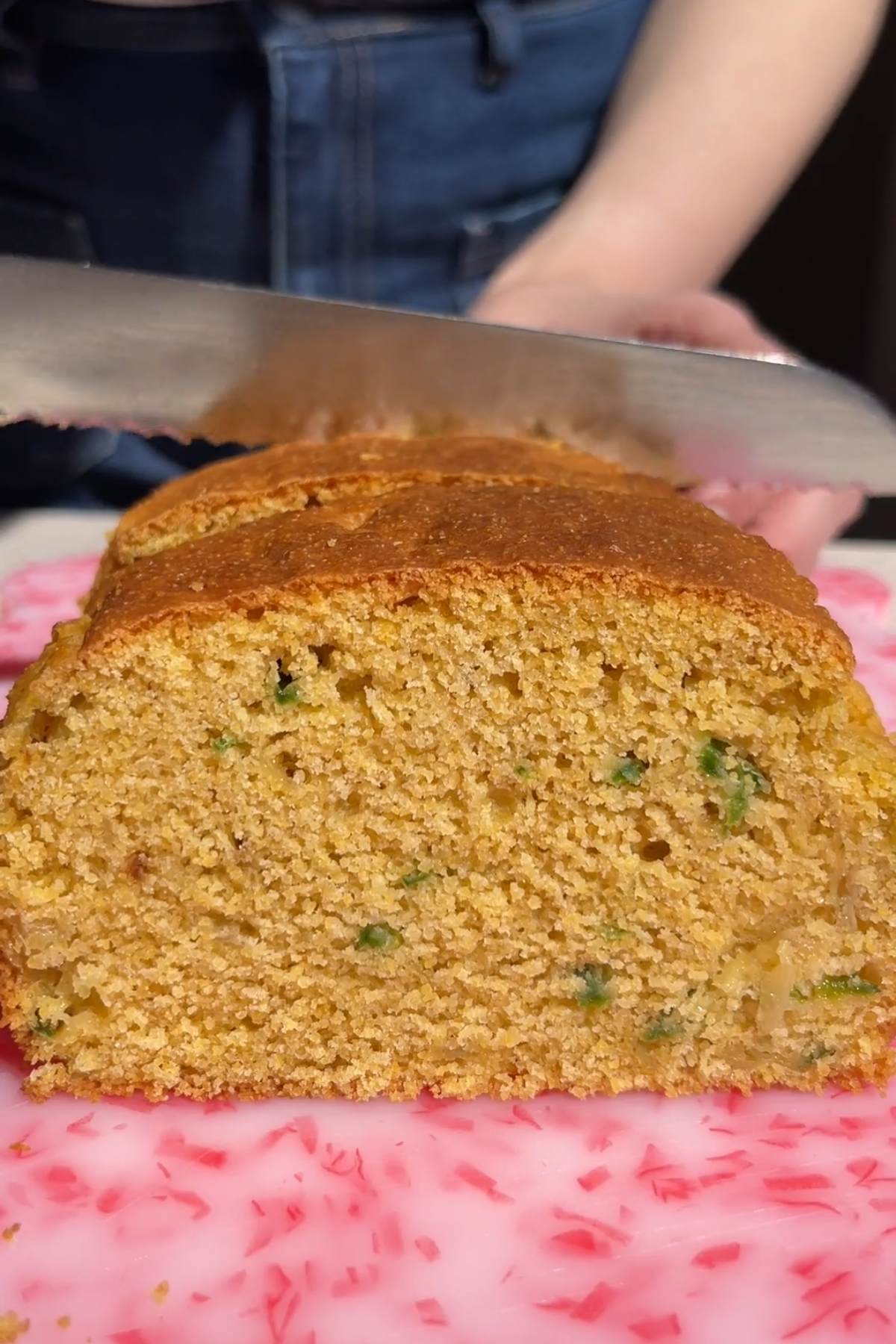 Close-up of sliced vegan jalapeño cornbread showing a moist crumb with jalapeño pieces.