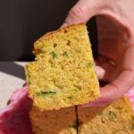 Square slice of vegan jalapeño cornbread held up to show the soft, tender interior.