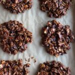 Six chocolate no bake cookies cooling on a parchment-lined baking tray.