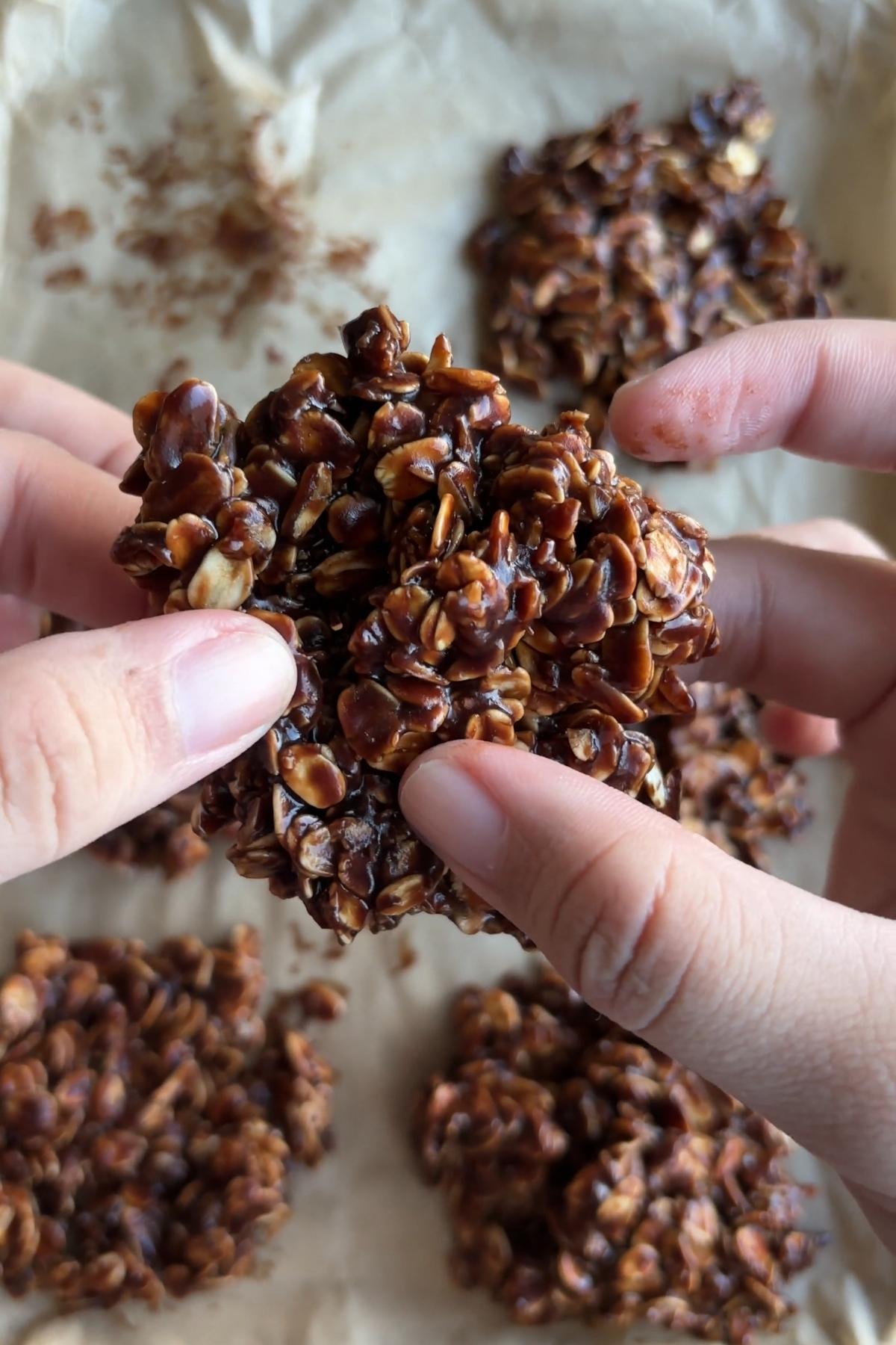 Chocolate no bake cookie held between two hands, showing its chewy oat texture.