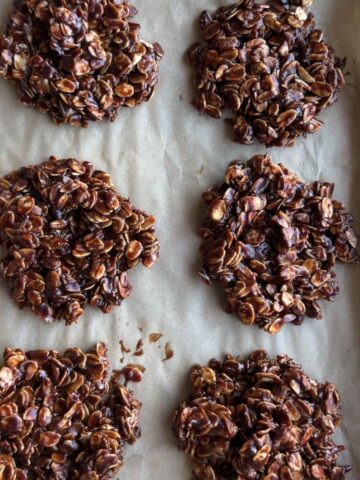 Six chocolate no bake cookies cooling on a parchment-lined baking tray.