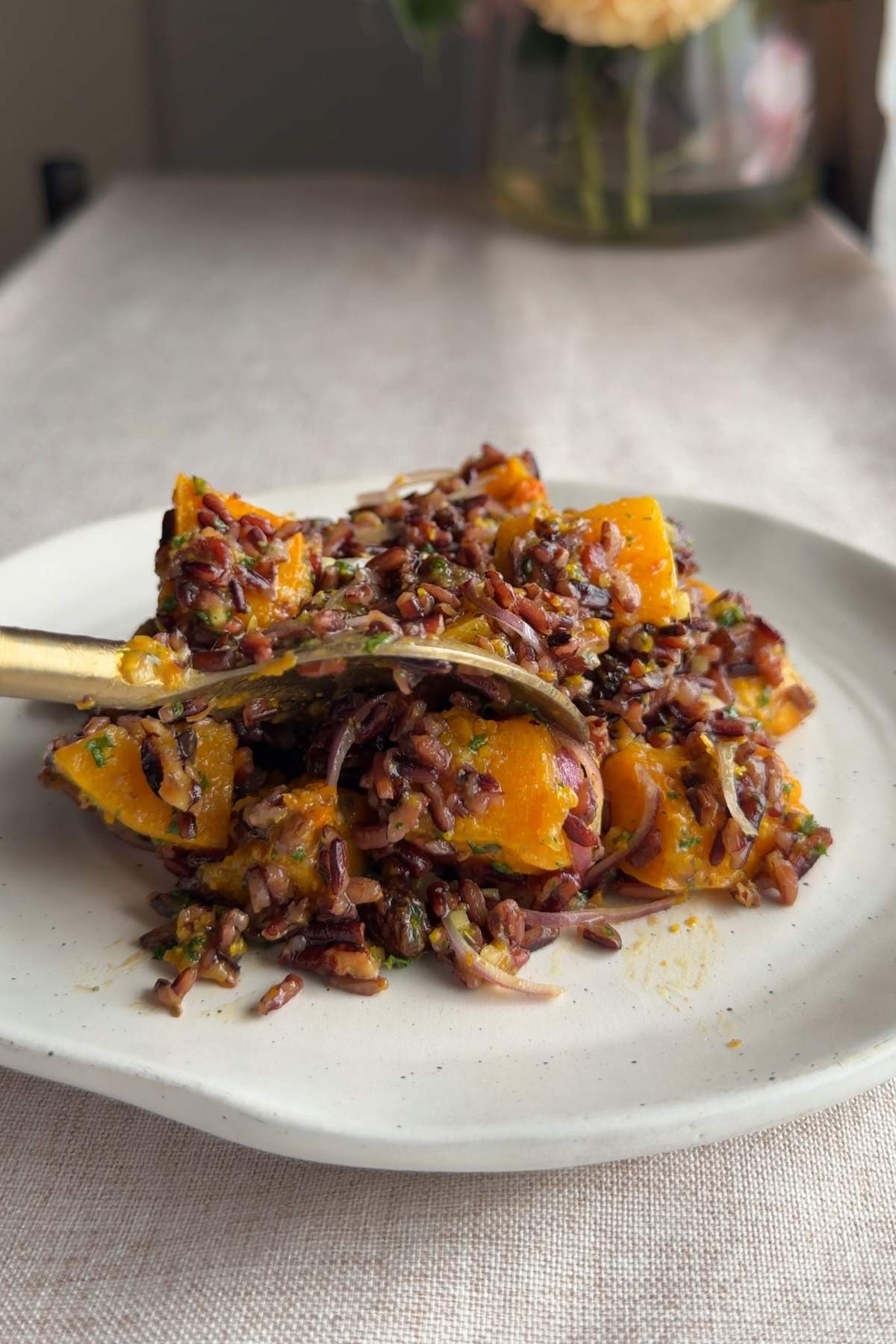 Wild rice salad with roasted butternut squash, pecans, and dried cranberries on a plate.