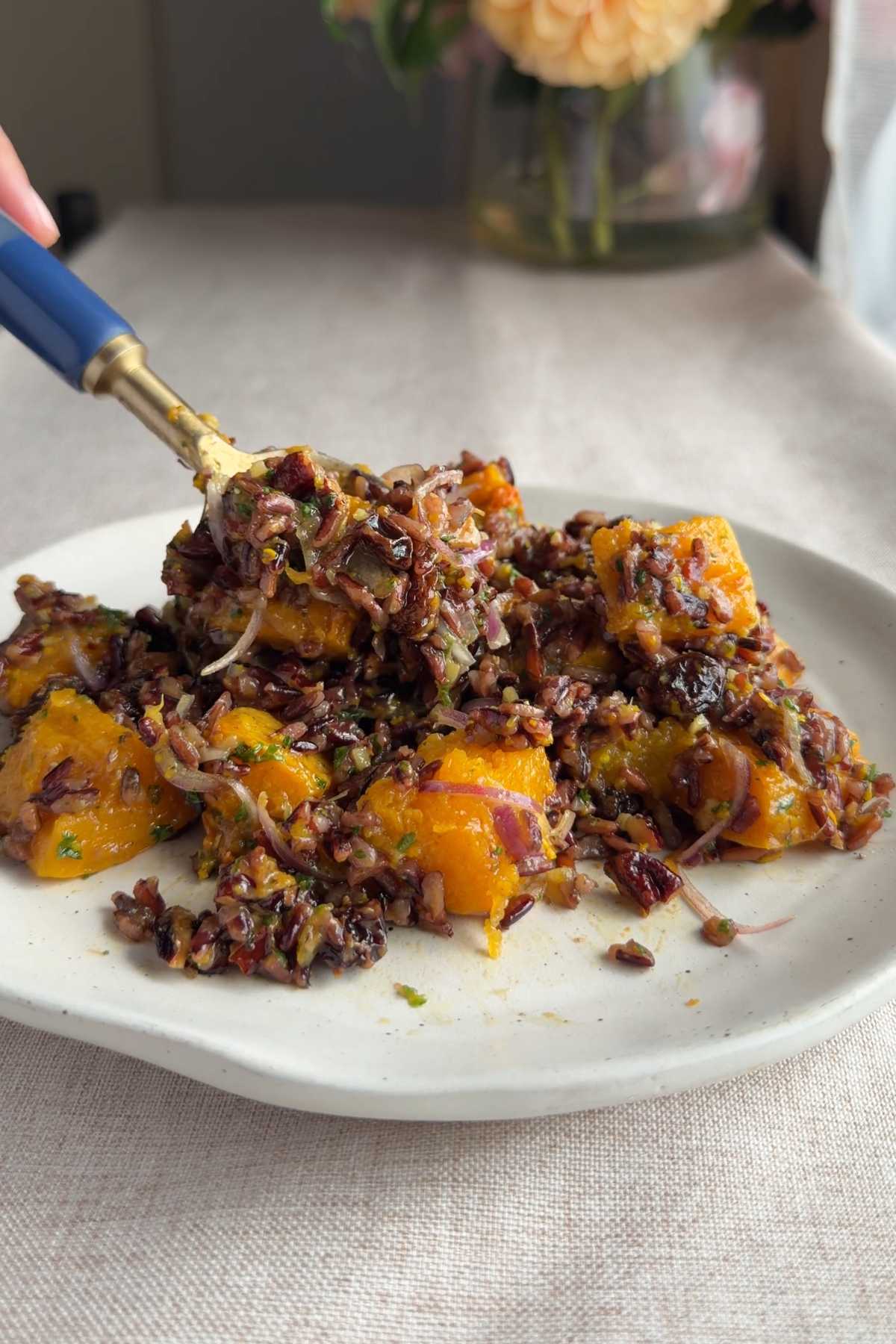 Spoon lifting a bite of wild rice salad with roasted butternut squash.