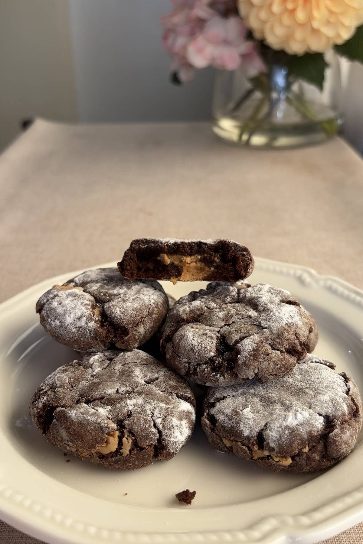 Chocolate crinkle cookies on a plate with a halved cookie on top revealing peanut butter filling.
