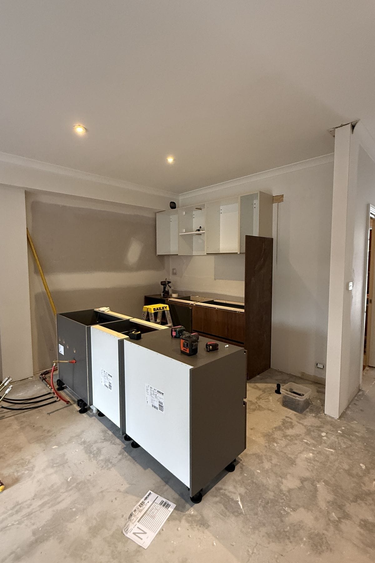 Base cabinets and upper carcasses fitted with a walnut panel leaning against the wall.