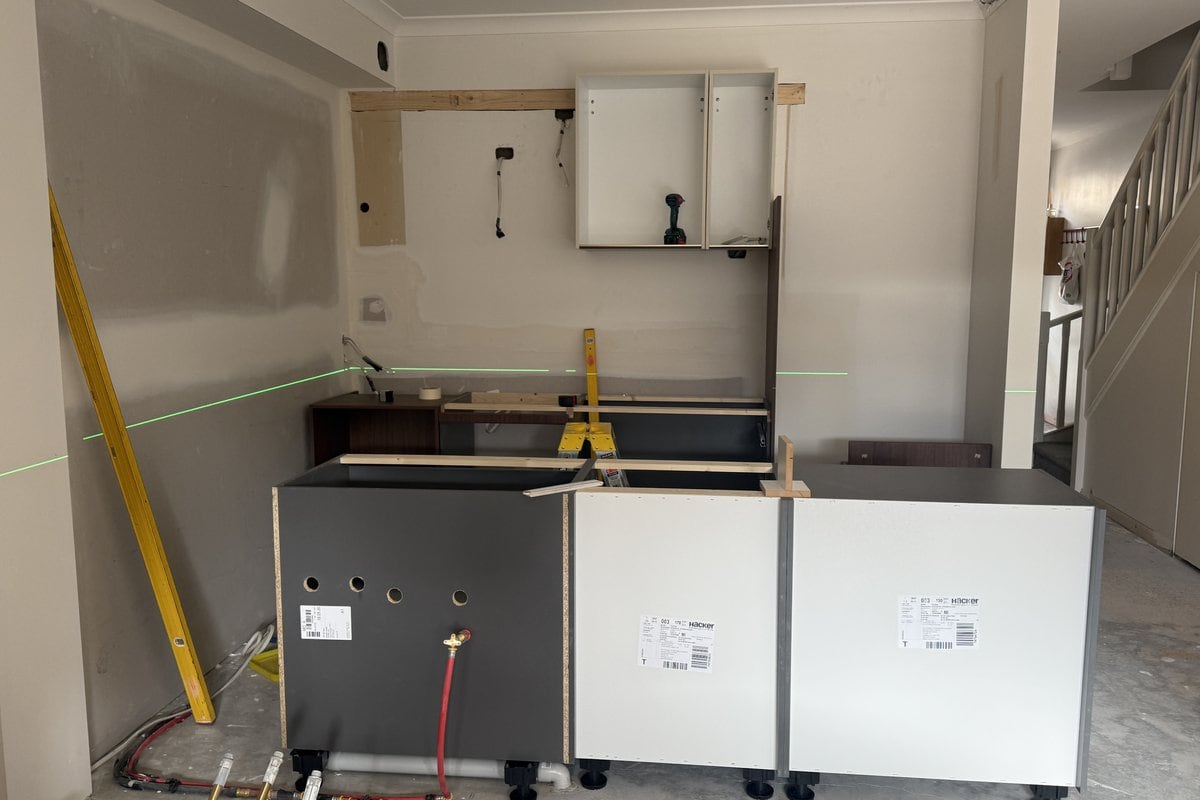 Base cabinets along a back wall with the first white upper cabinet carcass mounted above.