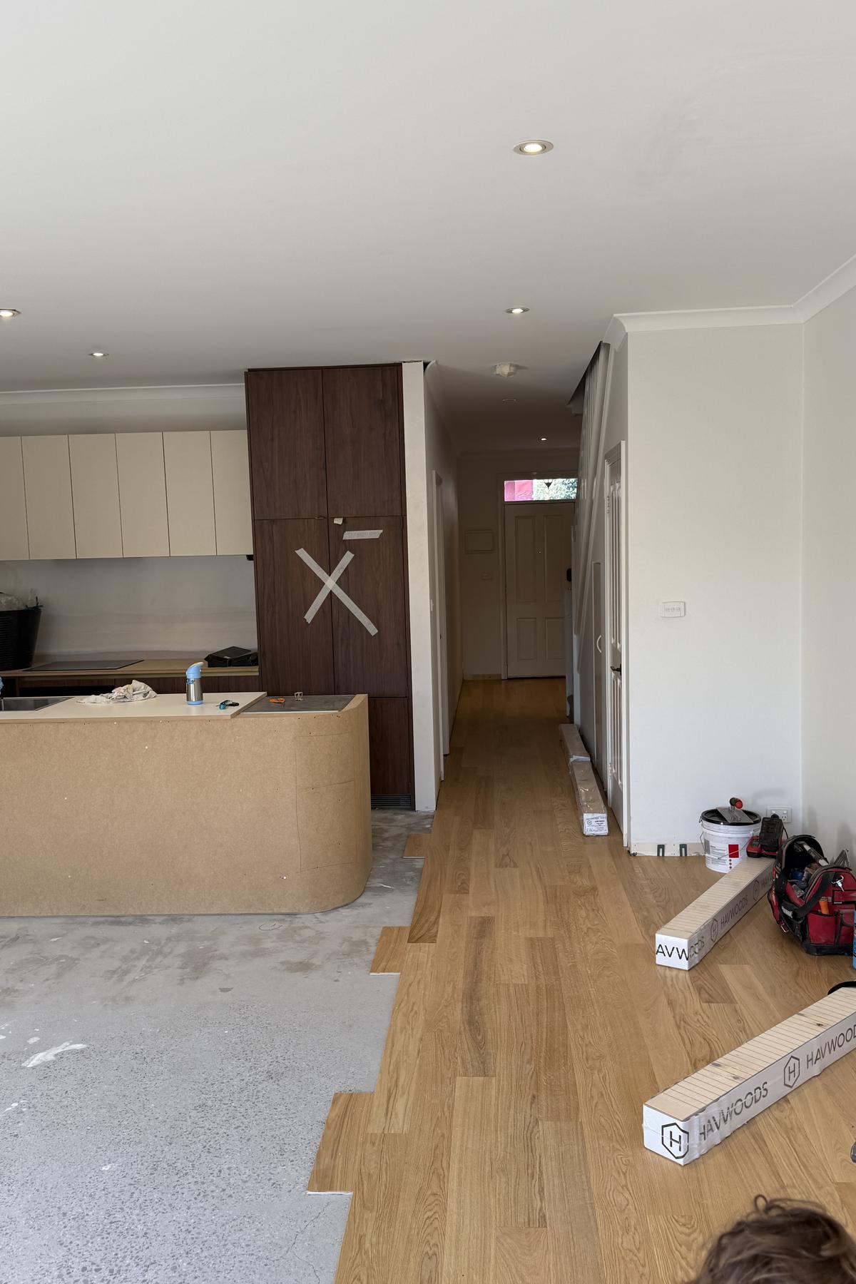 Oak floorboards partly laid across a ground floor with more boards stacked nearby.