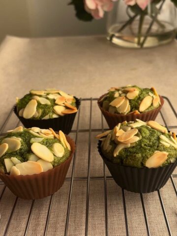 Side shot of four freshly baked matcha muffins in a cooling rack.
