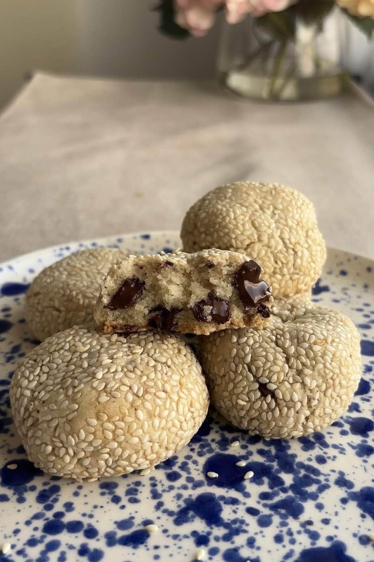 A broken cookie with melted chocolate resting on a stack of whole cookies.