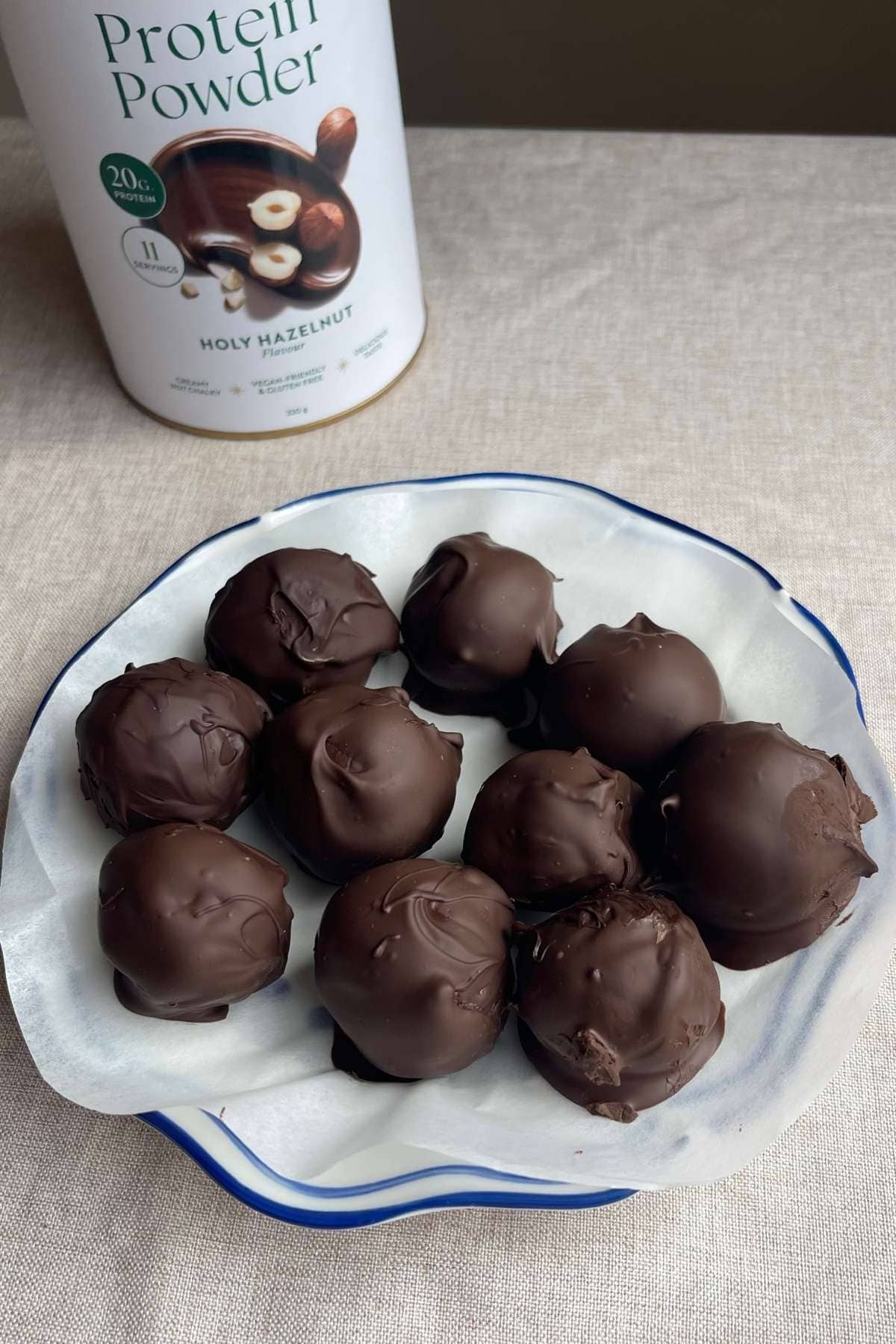 Chocolate-coated protein balls on a blue-rimmed plate.
